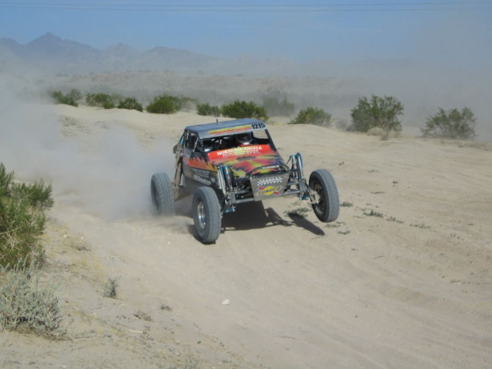 Flame-graphic off-road race buggy number 1215 racing through the desert