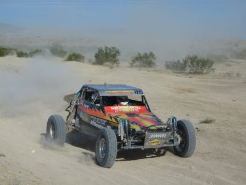 Front view of flame-graphic race buggy number 1215 with sponsor decals in the desert