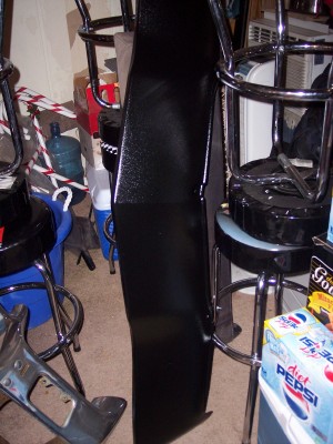 1972 Ford Ranchero - A black car part is propped up in a room with bar stools and boxes.