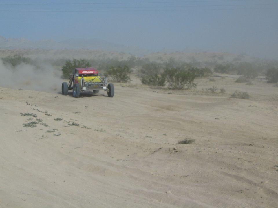 Yellow and red off-road buggy with Hi-Boy Racing decal driving away in the desert