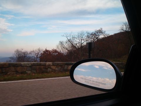 1994 Ford Probe - View from a vehicle's side mirror shows clouds and a distant landscape, with a warning about object proximity.