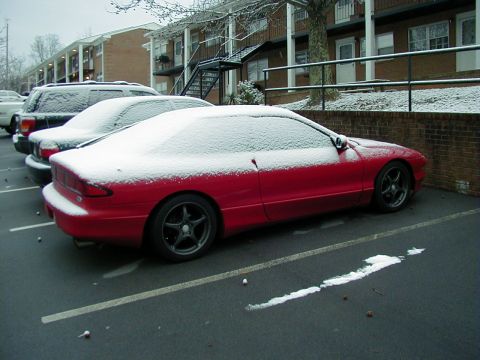 1997 Ford Probe - A red 1997 Ford Probe is parked in a lot covered in snow.