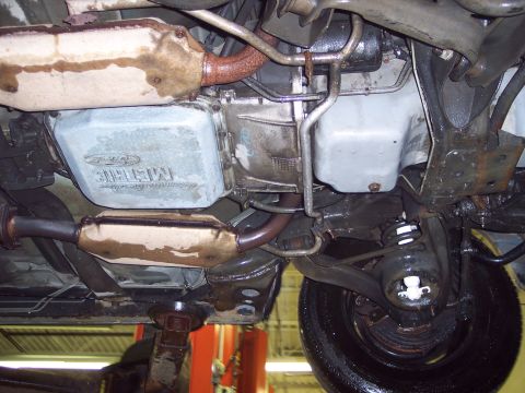 2001 Ford Crown Victoria - The underside of a vehicle is shown, focusing on the transmission and exhaust components. Text on the transmission pan indicates it is a Fo…