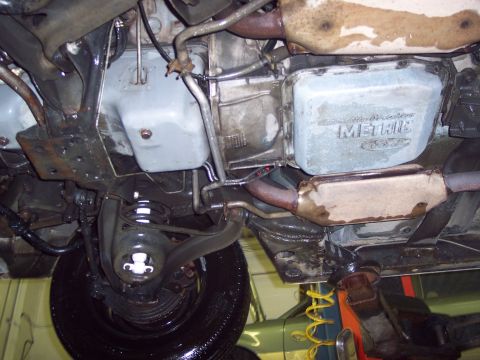 2001 Ford Crown Victoria - The underside of a vehicle reveals its transmission pan, exhaust system, and suspension components, with some visible markings.