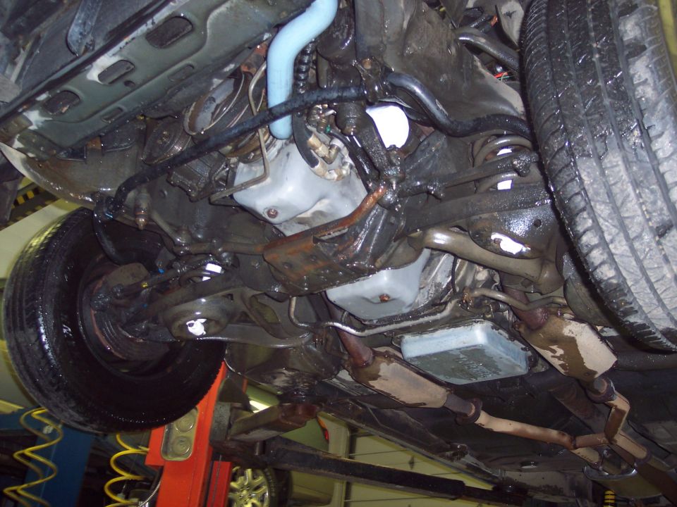 Undercarriage view of a vehicle showing suspension, exhaust, and tires