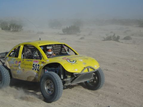 Yellow Beetle-bodied off-road race car number 502 with sponsor decals in the desert