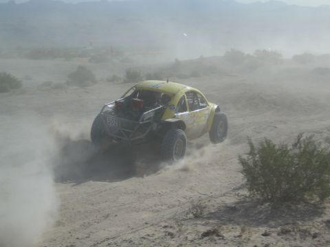 Rear view of yellow Beetle-bodied race buggy number 503 powering through desert dust