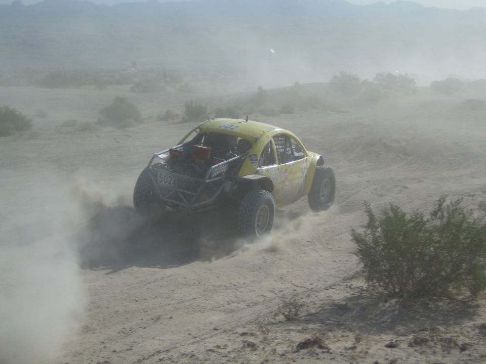 Rear view of yellow Beetle-bodied race buggy number 503 powering through desert dust