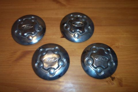 1998 Ford Crown Victoria - A set of four Ford hubcaps are displayed on a wooden table.