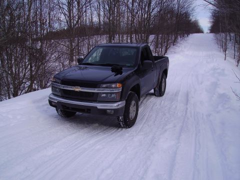 2000 Chevrolet Tahoe - A black Chevrolet Colorado pickup truck is parked on a snow-covered road surrounded by bare trees.