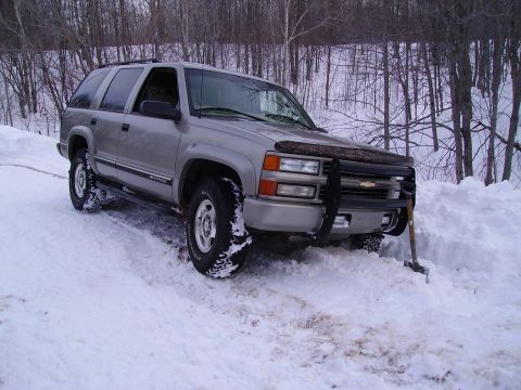 2000 Chevrolet Tahoe - This silver SUV appears to be stuck in a snowdrift, with a shovel leaning against the front bumper.