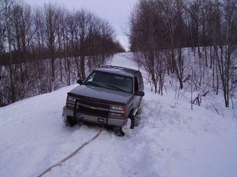 2000 Chevrolet Tahoe - This Chevrolet Tahoe appears to be stuck in a snowy ditch, with trees lining the path.
