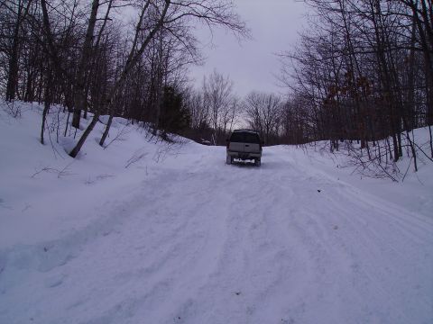 2000 Chevrolet Tahoe - A vehicle navigates a snowy path through a wooded area.