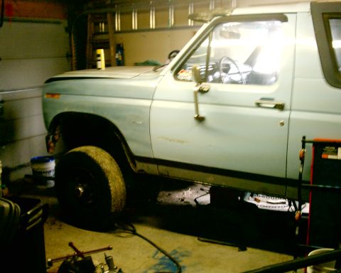 1985 Ford Bronco - Light blue Ford Bronco in a garage, likely undergoing maintenance or storage.