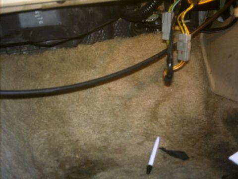1985 Ford Crown Victoria LTD - Close-up of car interior wiring and carpet, with a white pen on the floor.