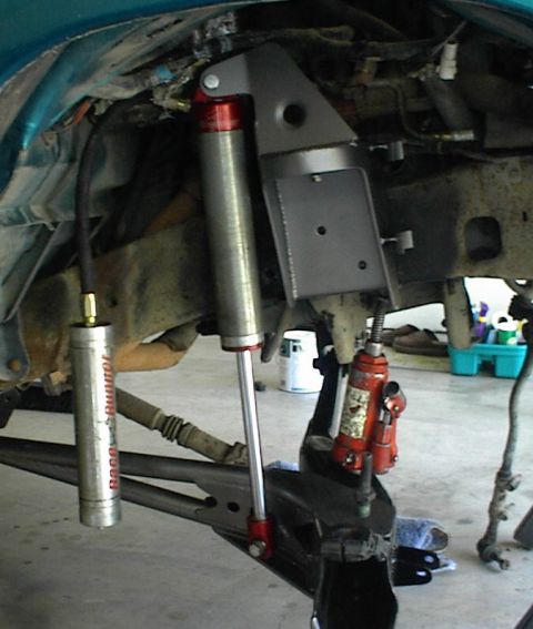 1984 Ford Bronco - Vehicle suspension work in progress, showing shock absorber and jack.