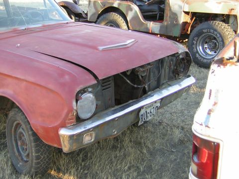 1963 Ford Falcon - The front of a red car, possibly a 1963 Ford Falcon, is shown with a missing grille and a Texas license plate.