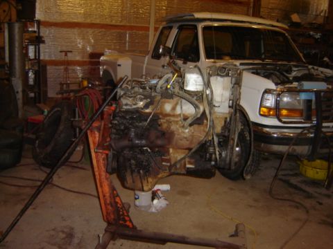 1992 Ford Bronco - The engine has been removed from the front of a white Ford truck in a workshop.