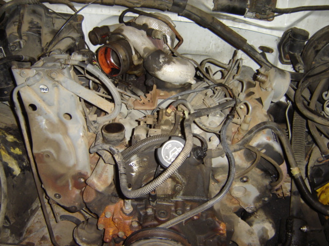Engine bay showing a turbocharger and various hoses and components. Oil cap visible