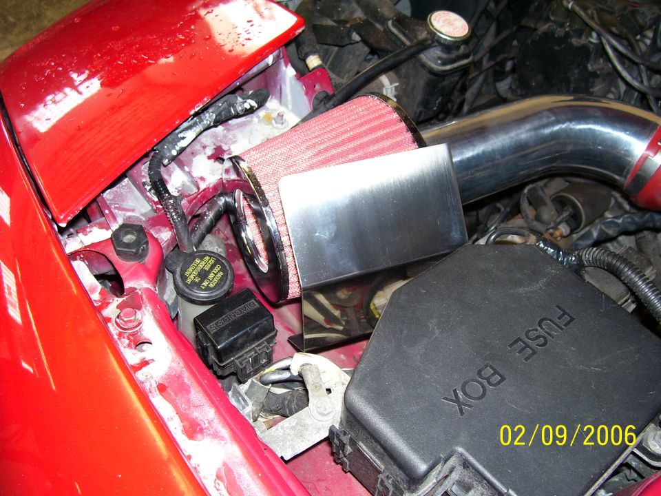 engine bay with red hood, aftermarket air filter, and fuse box