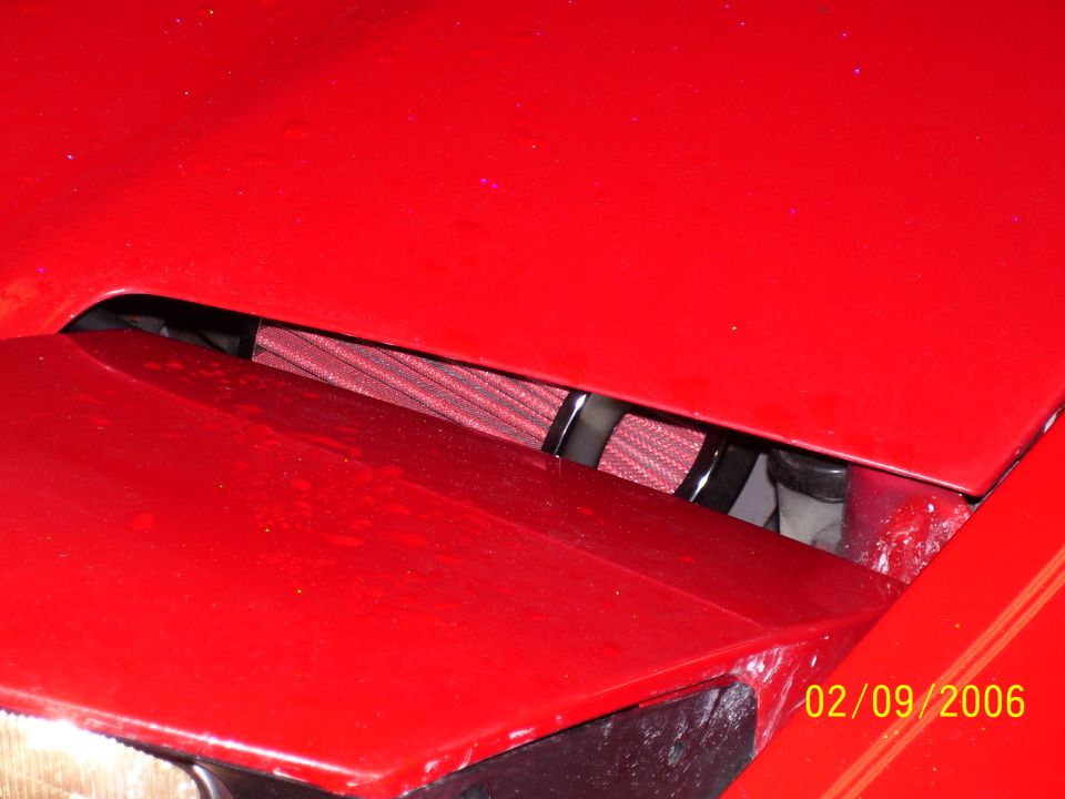 Red car engine bay with an exposed red aftermarket air filter visible under the hood