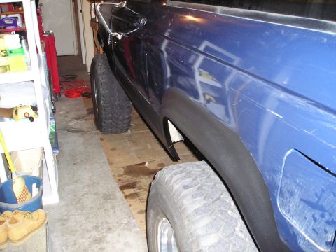 1986 Ford Bronco II - Side view of a blue SUV with prominent fender flares and off-road tires, possibly modified.