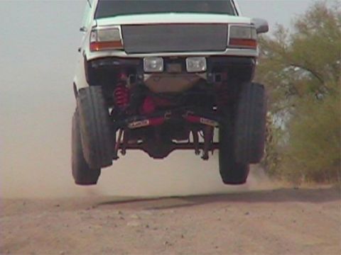 1993 Ford Bronco - Ford Bronco caught mid-air during a jump, showing its undercarriage and suspension.