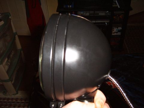 1993 Ford Bronco - A black headlight part is shown from the side, held by a person's hand.