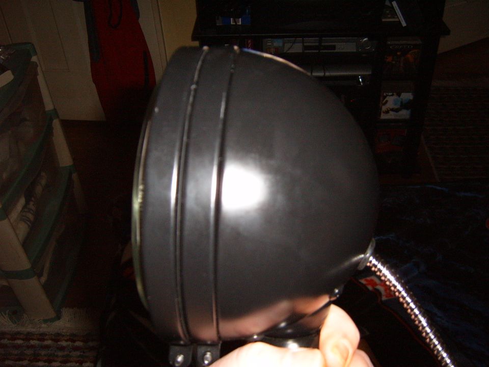 Black headlight with ribbed bezel, held by a hand