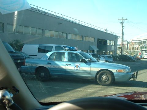 1999 Ford Crown Victoria - A Seattle Police car is parked outside a building, with other vehicles visible in the background.