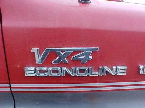 2000 Ford E350 - Close-up of a red Ford Econoline badge on a vehicle's side panel.