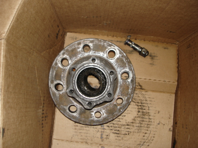 Wheel hub assembly with lug holes and a separate lug nut inside a cardboard box