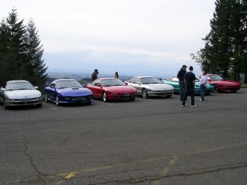 1996 Ford Probe - A group of Ford Probes are parked in a lot, with several people gathered around.