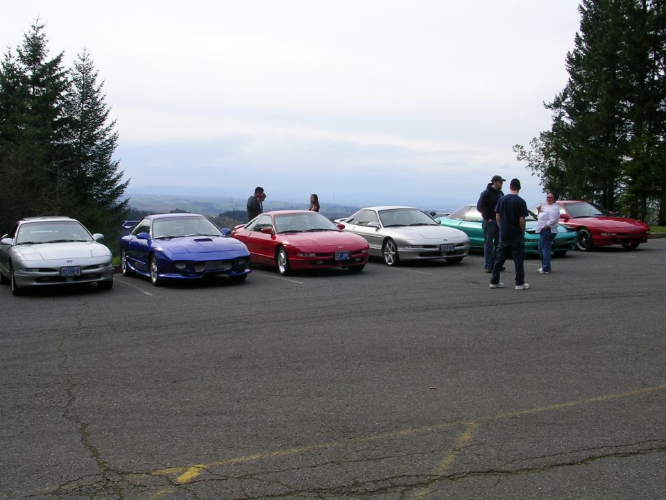 Several 1996 Ford Probes parked in a lot with people standing around them