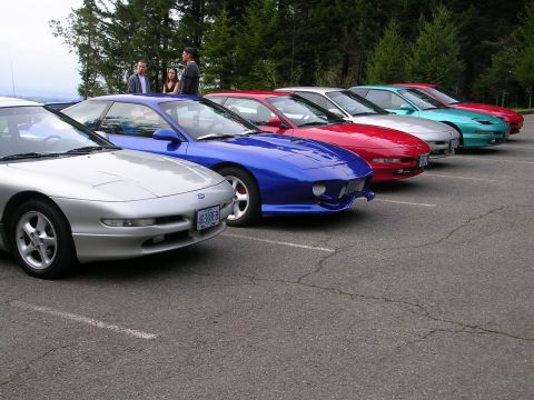 1996 Ford Probe - A line of Ford Probes are parked in a lot with trees in the background.