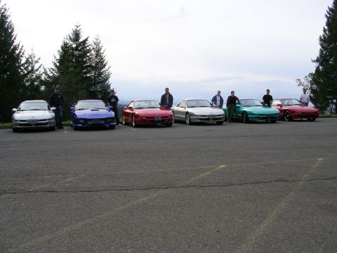1996 Ford Probe - A group of Ford Probe cars are gathered together in a parking lot with several people standing around them.