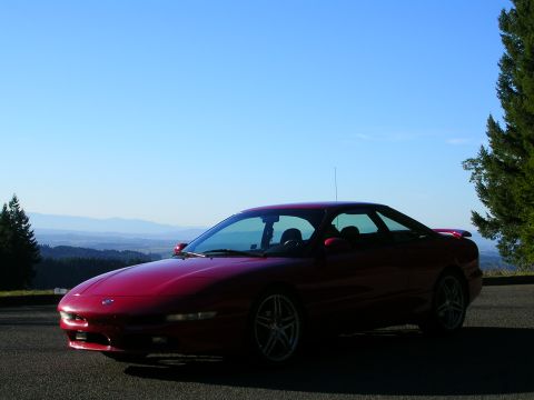 1996 Ford Probe - Red 1996 Ford Probe parked on a scenic overlook with mountains in the distance.