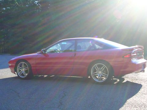 1996 Ford Probe - A red coupe is seen from the side with bright sun flares.