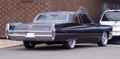 1972 Ford Ranchero - Rear view of a black 1965 Cadillac coupe with chrome trim and wire wheels.