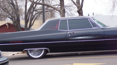 1972 Ford Ranchero - A black sedan with custom pinstriping and wire wheels is parked on a street.