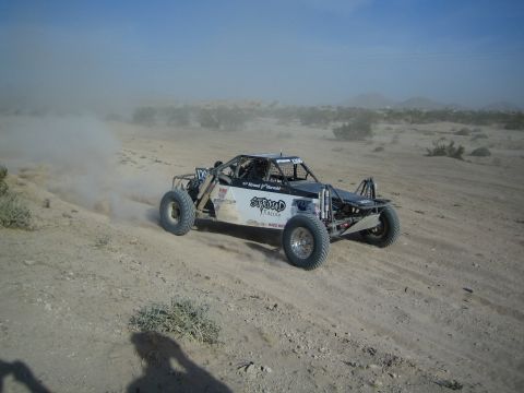 Open-frame off-road race buggy with Stroud Racing decals speeding through the desert