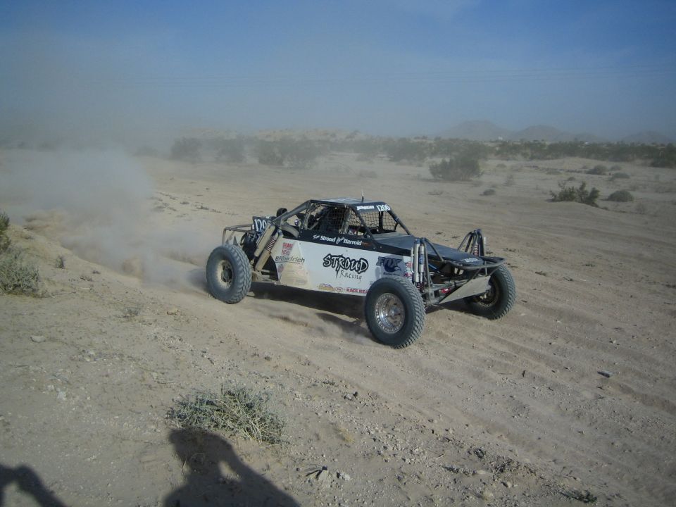 Open-frame off-road race buggy with Stroud Racing decals speeding through the desert