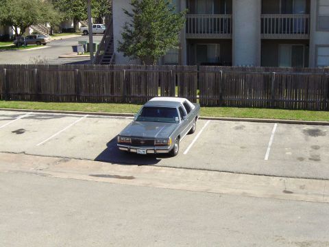 1988 Ford Crown Victoria LTD - A 1988 Ford Crown Victoria LTD is seen parked in a lot with a white roof.