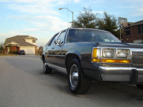 1988 Ford Crown Victoria LTD - A 1988 Ford Crown Victoria is parked on a residential street under a cloudy sky.