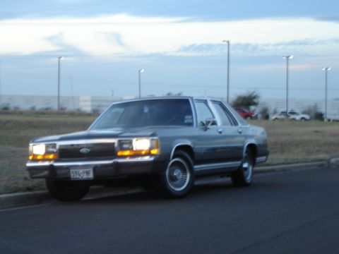 1988 Ford LTD Crown Victoria - A 1988 Ford Crown Victoria is parked curbside under a cloudy sky.