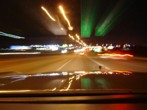 1988 Ford LTD Crown Victoria - A blurry, motion-filled view from inside a vehicle at night, showing the dashboard and illuminated highway ahead.