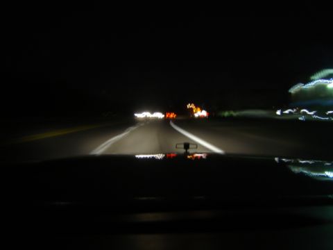 1988 Ford LTD Crown Victoria - Driving at night, headlights illuminate the road ahead and other vehicles' lights are visible in the distance.