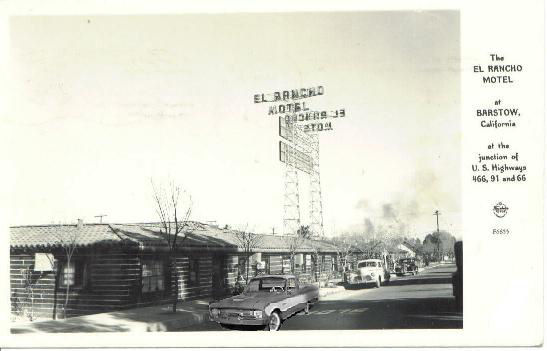 Old photograph of El Rancho Motel sign and log cabin style buildings with cars on the road