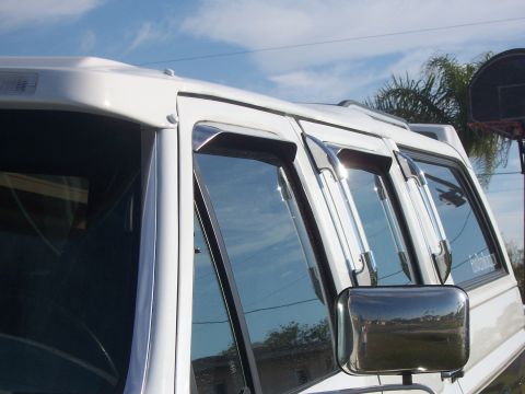 1993 Ford C-350 (Centurion Conversions) - Chrome vent visors are attached to the windows of a white van.