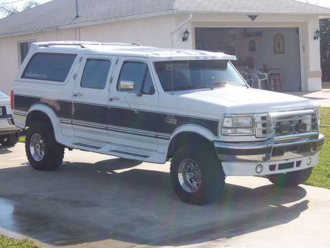 1993 Ford C-350 (Centurion Conversions) - This white conversion van features a two-tone black and white paint scheme with chrome accents and a visor above the windshield.